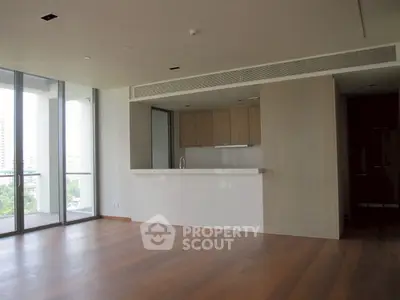 Spacious modern living room with open kitchen and large windows.
