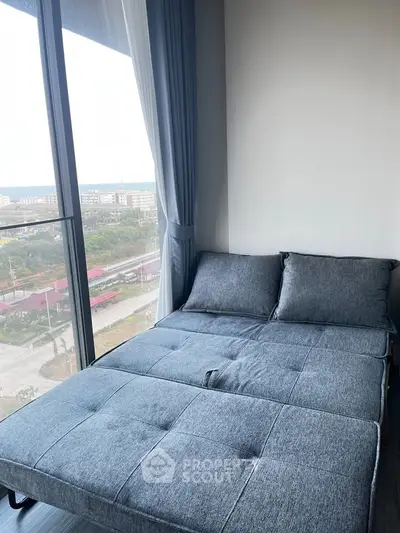 Modern bedroom with large window offering stunning city view and stylish gray bedding.