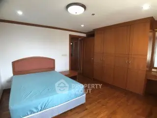 Spacious bedroom with wooden flooring and built-in wardrobe in modern apartment.