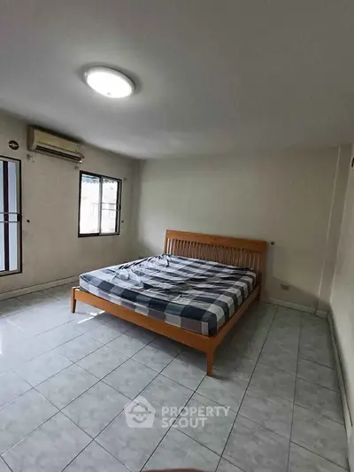 Spacious bedroom with large windows and tiled flooring