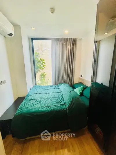 Cozy bedroom with large window and green bedding in modern apartment