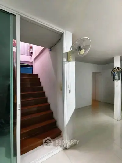 Spacious interior with wooden staircase and sliding glass door, ideal for modern living.