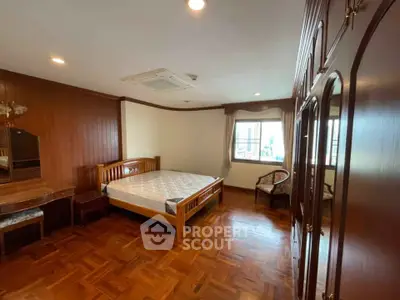 Spacious bedroom with wooden flooring and elegant furniture in a cozy home.