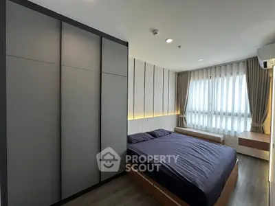 Modern bedroom with sleek design, large window, and ample storage space.