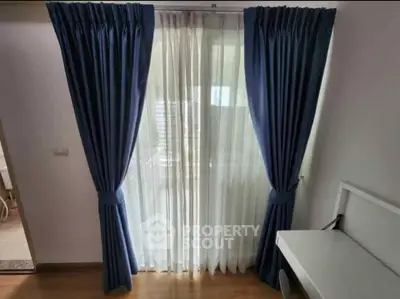 Spacious room with elegant blue curtains and natural light, perfect for a serene living space.