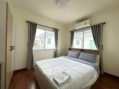Cozy bedroom with striped bedding, large windows, and air conditioning in a modern home.