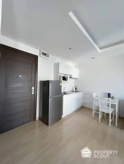 Bright and modern kitchen with sleek white cabinetry and stainless steel appliances, complemented by warm wooden flooring and a cozy dining area.