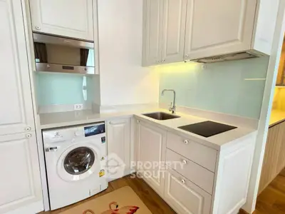 Modern kitchen with washing machine and sleek cabinetry in compact layout.