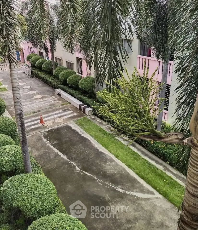 Charming residential building exterior with lush greenery and well-maintained pathways.