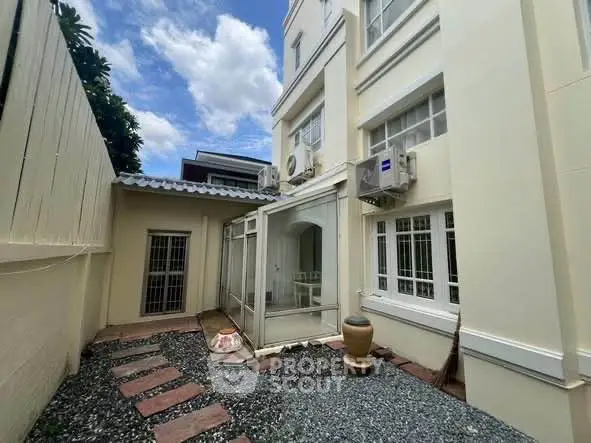 Charming exterior view of a modern home with a small garden and air conditioning units.