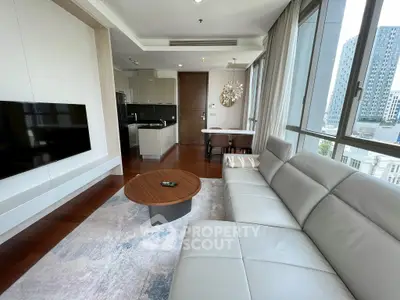 Modern living room with sleek furniture and large windows offering city views.