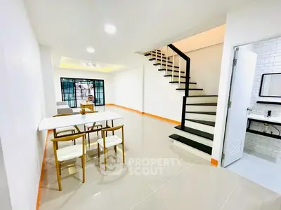 Modern open-plan living area with sleek staircase and dining setup