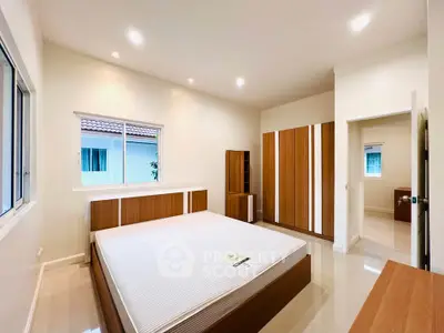 Spacious modern bedroom with sleek wooden furniture and large windows.