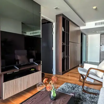 Modern living room with sleek furniture and wooden flooring, featuring a large TV and stylish decor.