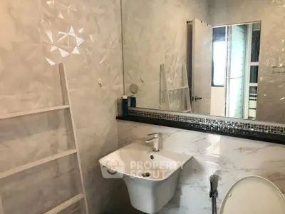 Modern bathroom with sleek sink and large mirror, featuring elegant tile design.