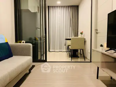 Modern living room with stylish furniture and open layout leading to dining area.