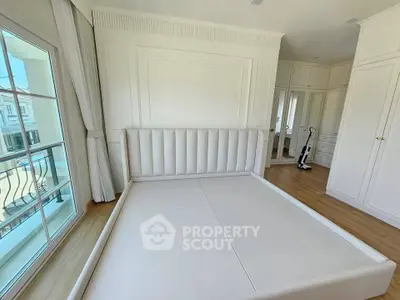Spacious bedroom with elegant white decor and large windows for natural light.