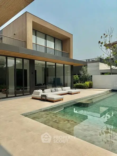 Luxurious modern home with sleek pool and stylish outdoor seating area.