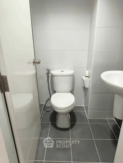 Modern bathroom with sleek white fixtures and tiled flooring, perfect for contemporary living.