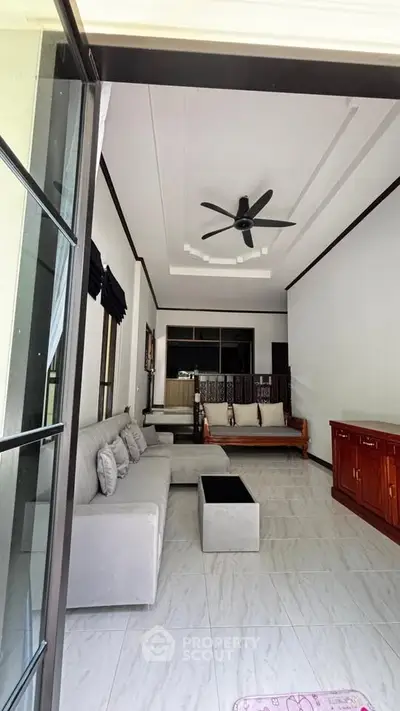 Spacious living room with modern furniture and ceiling fan, perfect for relaxation.
