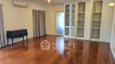 Spacious living room with polished wooden floors and built-in cabinets