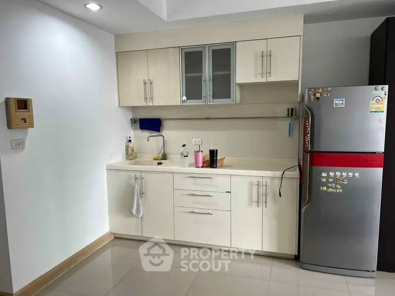 Modern kitchen with sleek cabinetry and stainless steel fridge in a bright apartment.