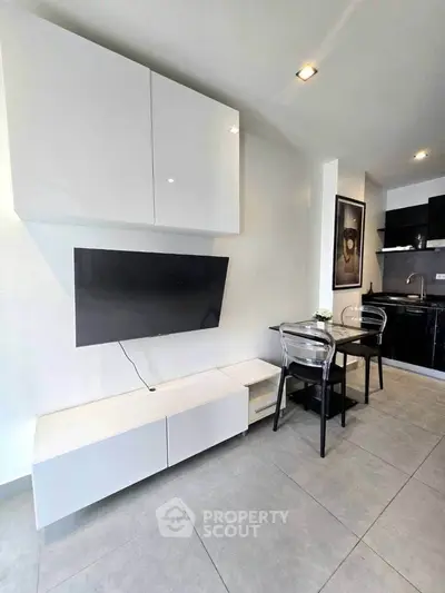 Modern living room with sleek TV setup and dining area in stylish apartment.