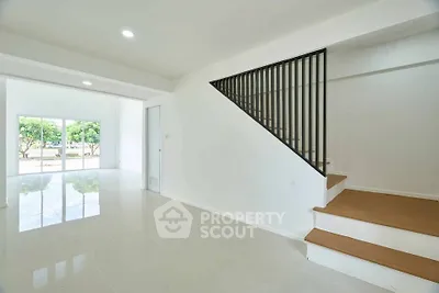 Spacious modern living room with staircase and large windows offering natural light and garden view.
