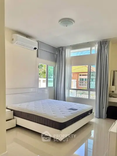 Bright and airy bedroom with large windows and modern furnishings, perfect for a cozy retreat.