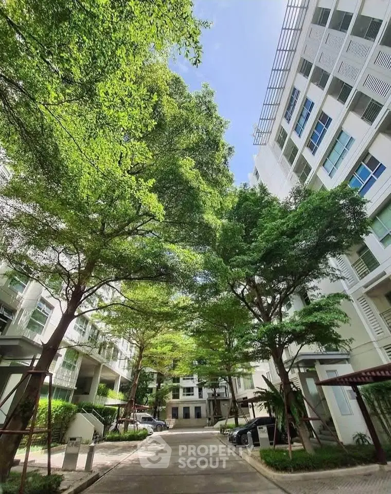 Modern apartment building with lush green trees and clear blue sky