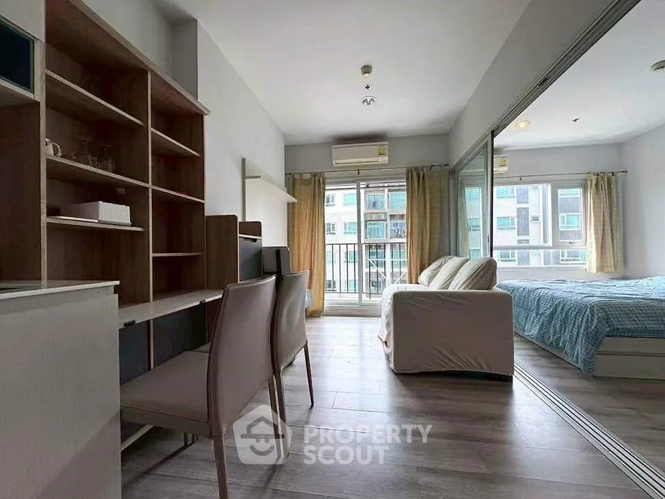 Modern studio apartment with open layout, featuring a cozy living area, study desk, and large windows for natural light.