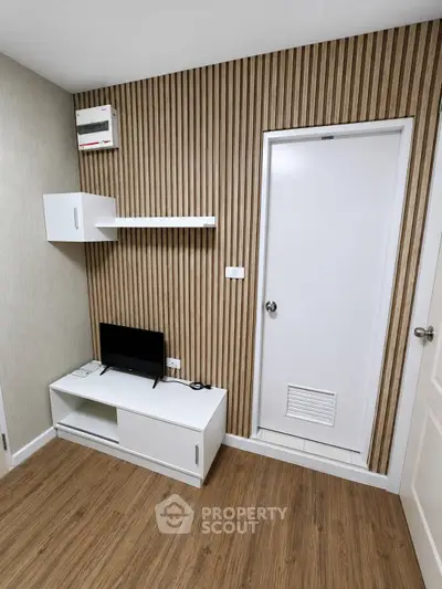 Modern minimalist study room with wood panel accent wall and sleek white furniture.