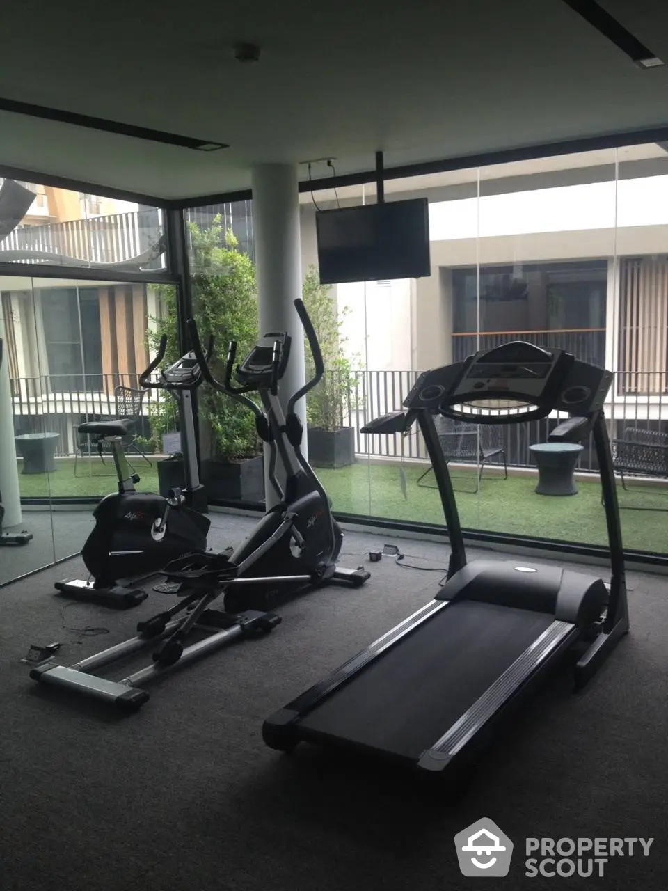 Modern residential gym with state-of-the-art equipment, floor-to-ceiling windows, and a serene view, ideal for fitness enthusiasts.