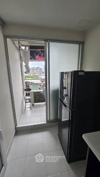 Modern kitchen with balcony access and sleek refrigerator in urban apartment.