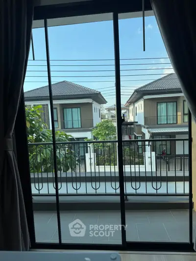 Charming balcony view of modern suburban homes with lush greenery and clear blue sky.