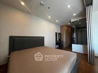 Modern bedroom with elegant design and glass-enclosed shower area, featuring warm lighting and sleek furnishings.