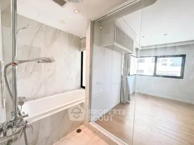 Luxurious bathroom with marble tiles and glass partition in modern apartment