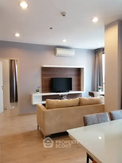 Modern living room with beige sofa, wall-mounted TV, and air conditioning in a stylish apartment.
