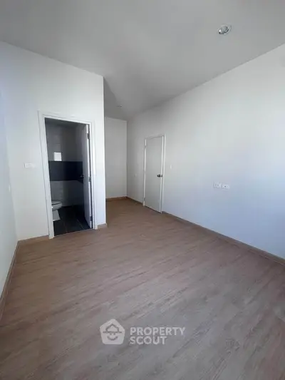 Spacious unfurnished room with wooden flooring and attached bathroom, ideal for customization.