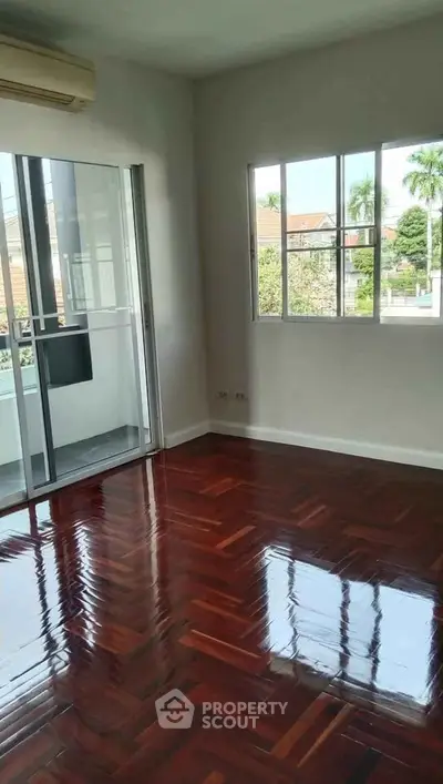 Spacious room with polished wooden floors and balcony access