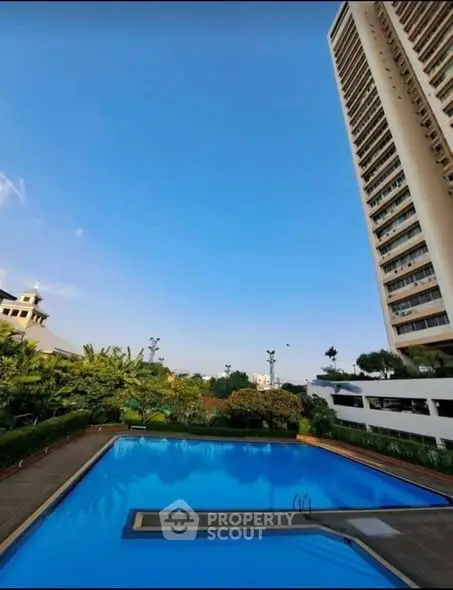 Luxurious high-rise building with stunning pool and lush greenery, perfect for modern living.