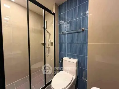 Modern bathroom with glass shower and blue tile accent wall
