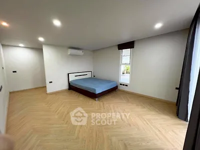 Spacious modern bedroom with wooden flooring and natural light