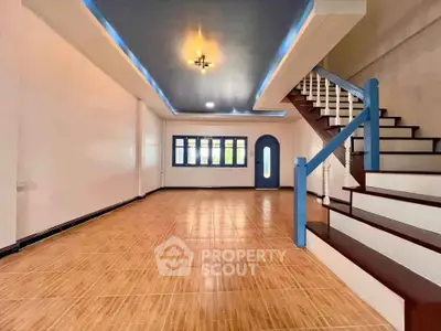 Spacious open-plan living area with modern staircase and stylish ceiling lighting.