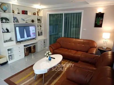 Cozy living room with leather sofas and built-in shelving, perfect for relaxation and entertainment.