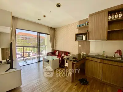 Charming open-layout living room with balcony view, featuring modern kitchen and cozy seating area.