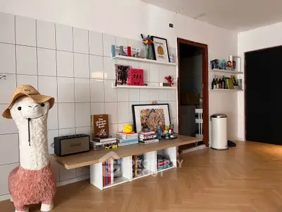 Stylish living room with modern decor and unique llama statue, featuring open shelving and parquet flooring.