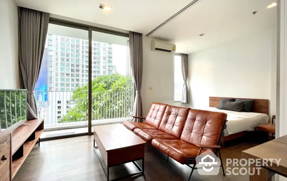 Modern studio apartment with balcony and city view, featuring stylish furniture and natural light.