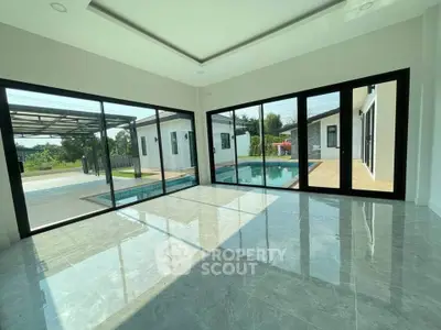 Spacious modern living room with large windows overlooking a private pool and garden.