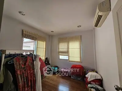 Cozy bedroom with wooden flooring and air conditioning, featuring ample natural light and storage space.